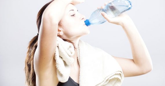 A woman drinking water after exercising