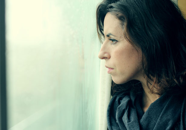 CLose up of woman looking out of the window looking sad
