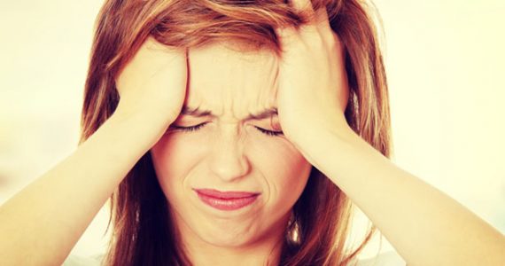 A woman holding her head in pain representing a migraine