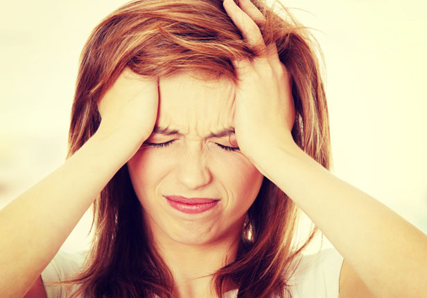 A woman holding her head in pain representing a migraine