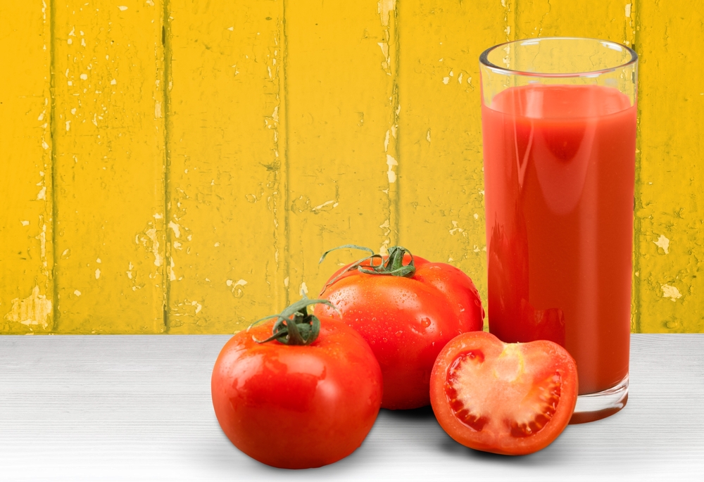 Whole tomatoes and a glass of tomato juice