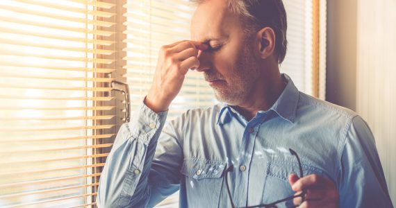 CLose up of a man holding his head to represent being tired and headachy