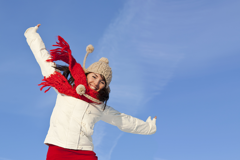 Close up on woman in winter hat and scarf jumping with energy
