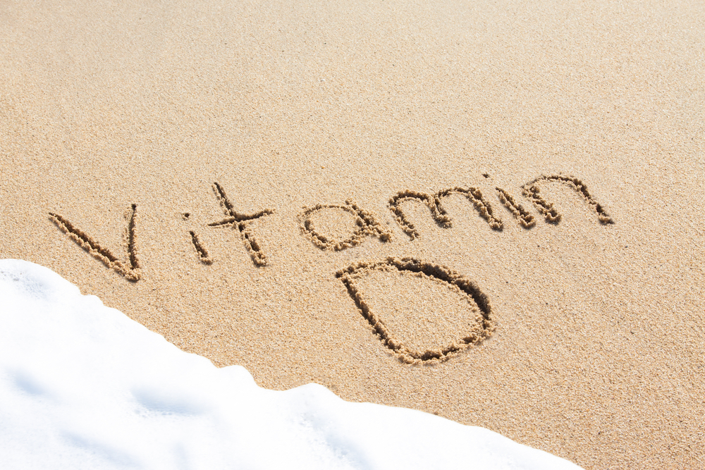 The words Vitamin D written in the sand with the sea coming in