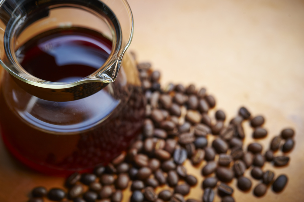 A jug of coffee surrounded by coffee beans