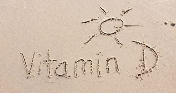 Vitamin D and a sunshine written into the sand on beach