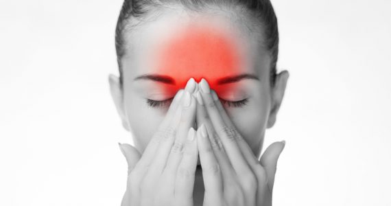 Woman in black and white with red highlighting over forehead to denote headache