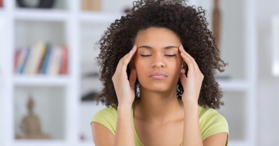 Woman with anxiety with eyes closed and touching hands to temples