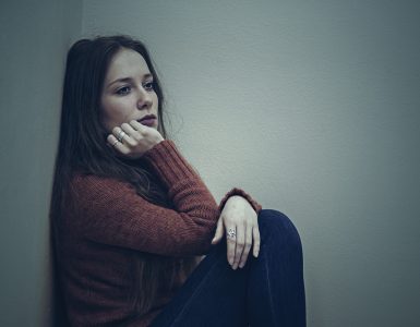 Woman sitting on floor looking sad demonstrating low mood