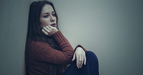 Woman sitting on floor looking sad demonstrating low mood