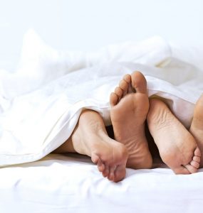 Two pairs of feet sticking out from the end of the bed to represent sex drive and libido