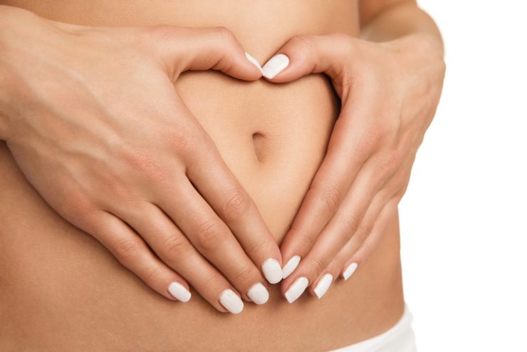 Close up on stomach with hands making a heart shape to show good digestion