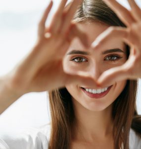 Woman using hands to make a heart showcasing her eyes to represent good eye health