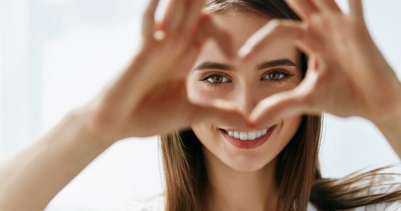 Woman using hands to make a heart showcasing her eyes to represent good eye health