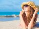Happy woman on holiday lying on beach smiling up at the sky