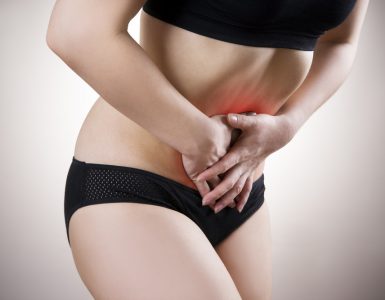 Woman holding lower abdomen to represent cystitis