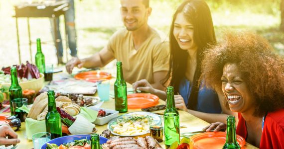 A group of people have fun at a bbq eating outdoors