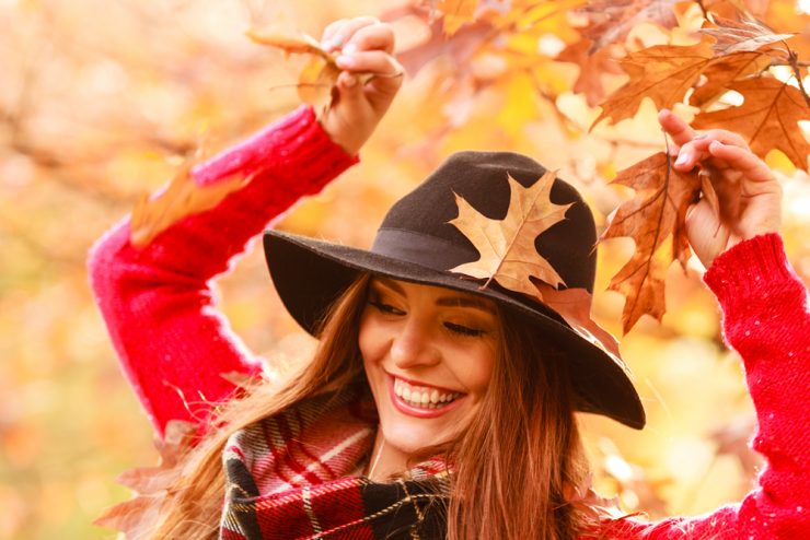 Close up of happy woman in autumn with falling leaves