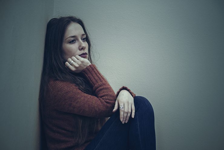 Woman sitting on floor looking sad to represent mental health