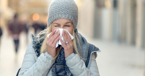 Woman with cold blowing her nose