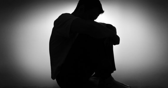 BLack and white picture of a man with depression and low mood, with his head in his hands