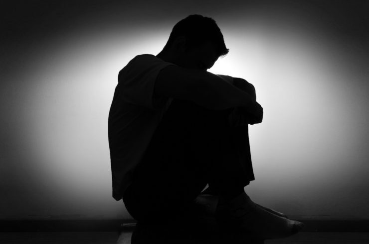 BLack and white picture of a man with depression and low mood, with his head in his hands