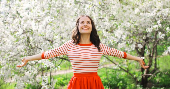 Happy young woman in front of a blossom tree to show spring season