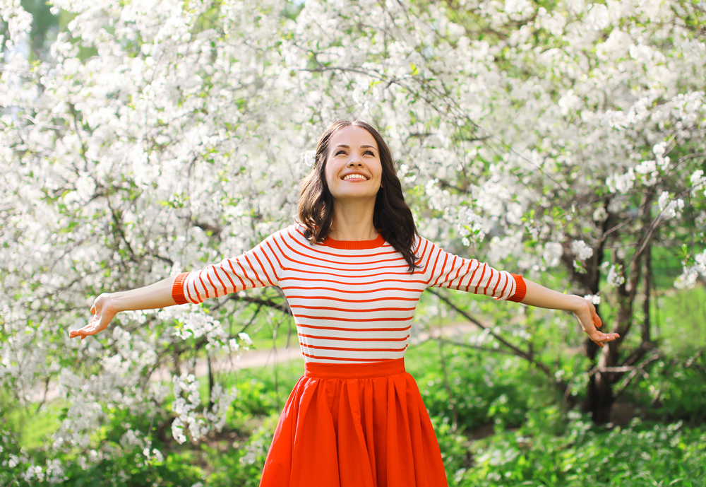 Happy young woman in front of a blossom tree to show spring season