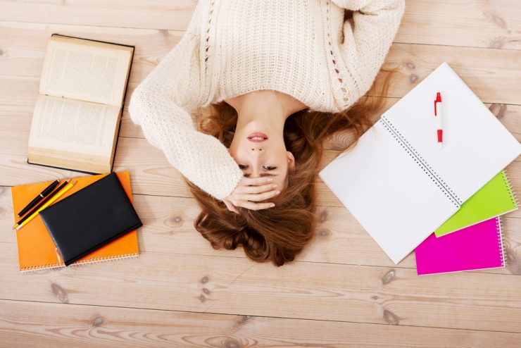 Woman lying on floor surrounded by work representing stress