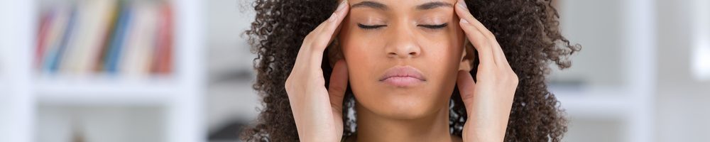 Woman holding hands to the side of her head to represent a headache