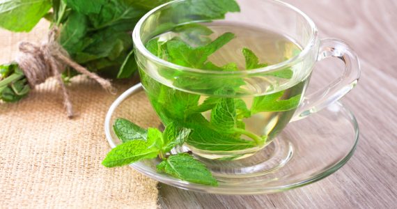A cup of fresh mint tea and a bunch of fresh mint