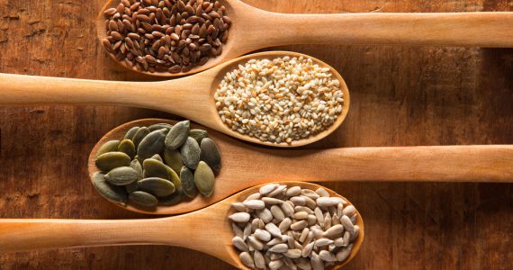 A range of seeds on individual wooden spoons