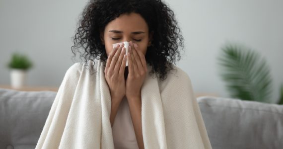 Woman with a cold sitting with a blanket on