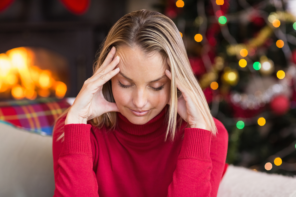 Woman with head in hands at Christmas to repesent a hangover headache