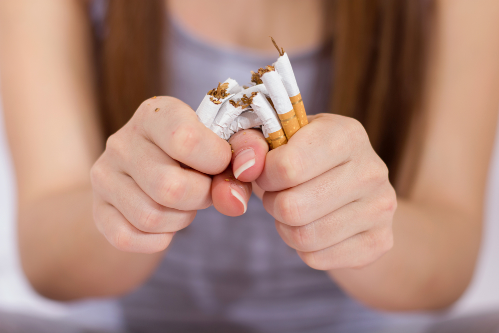 Close up of woman snapping a handful of cigarettes in half