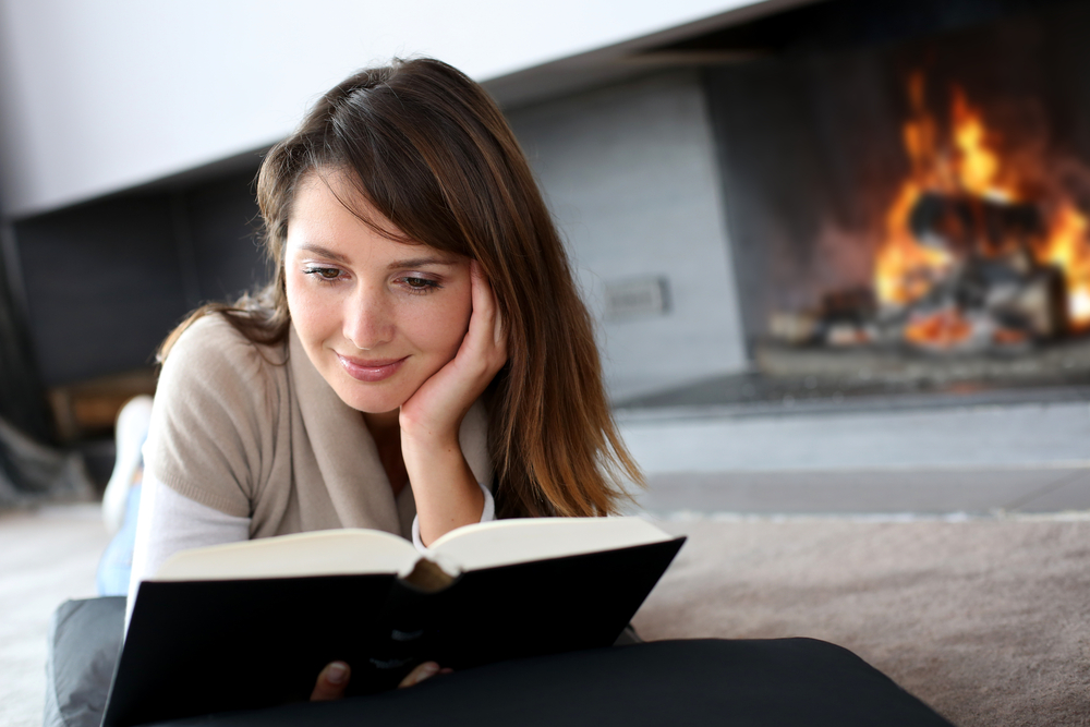 Close jup of a woman reading a book by the fireside