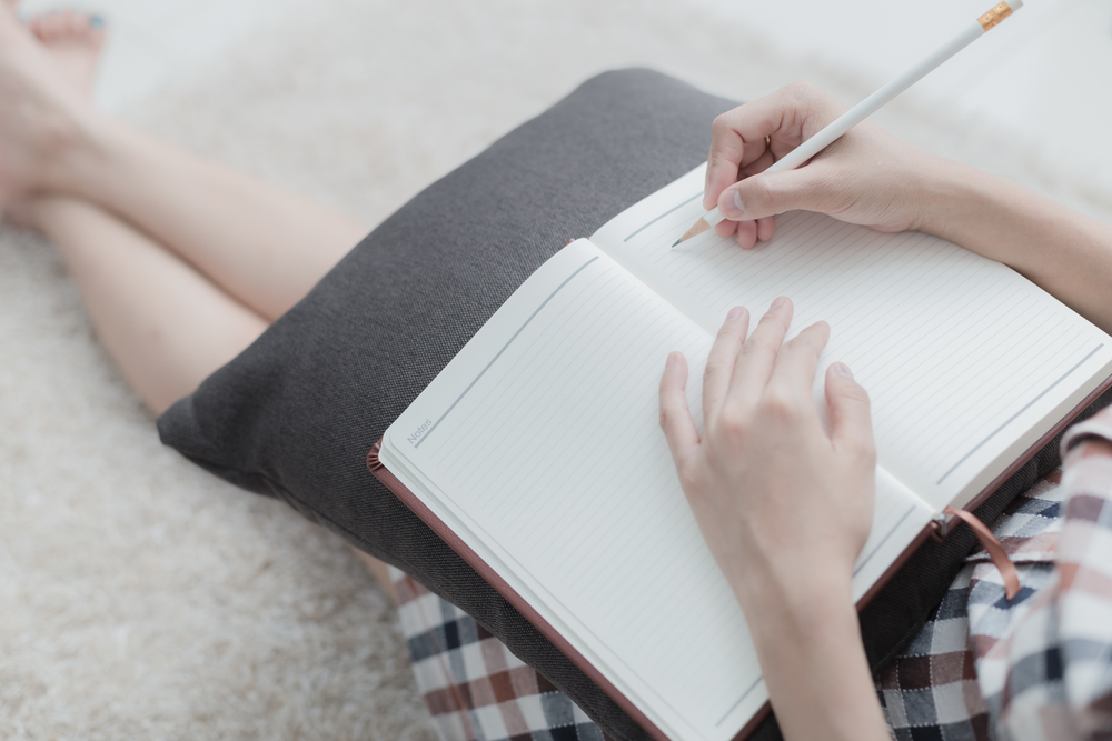 Close up of woman writing in note pad