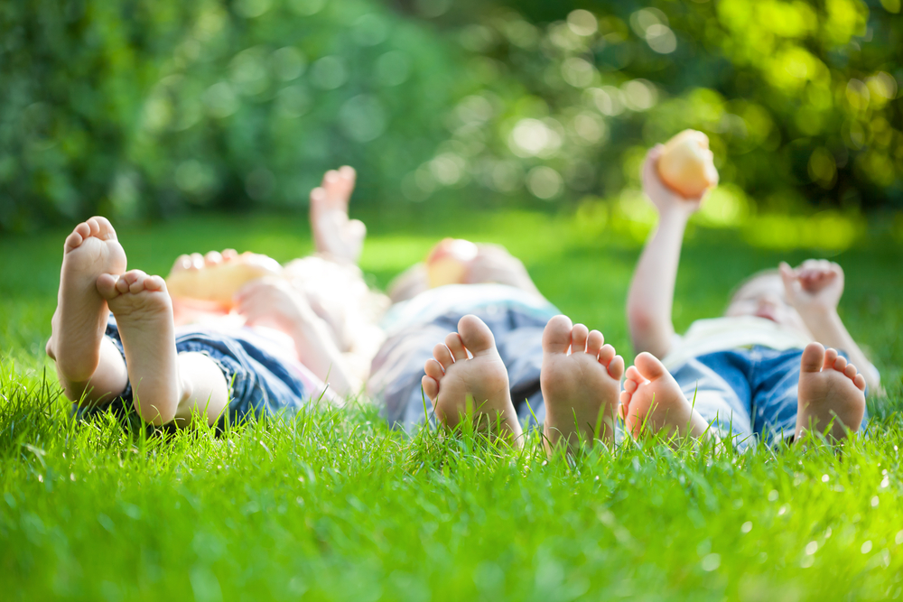 CHIldren lying down in the grass in a park to represent spending time in green spaces