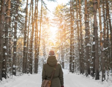 Woman taking a winter walk in snowy woodland