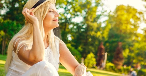 Middle aged woman enjoying the outdoors sitting in a park