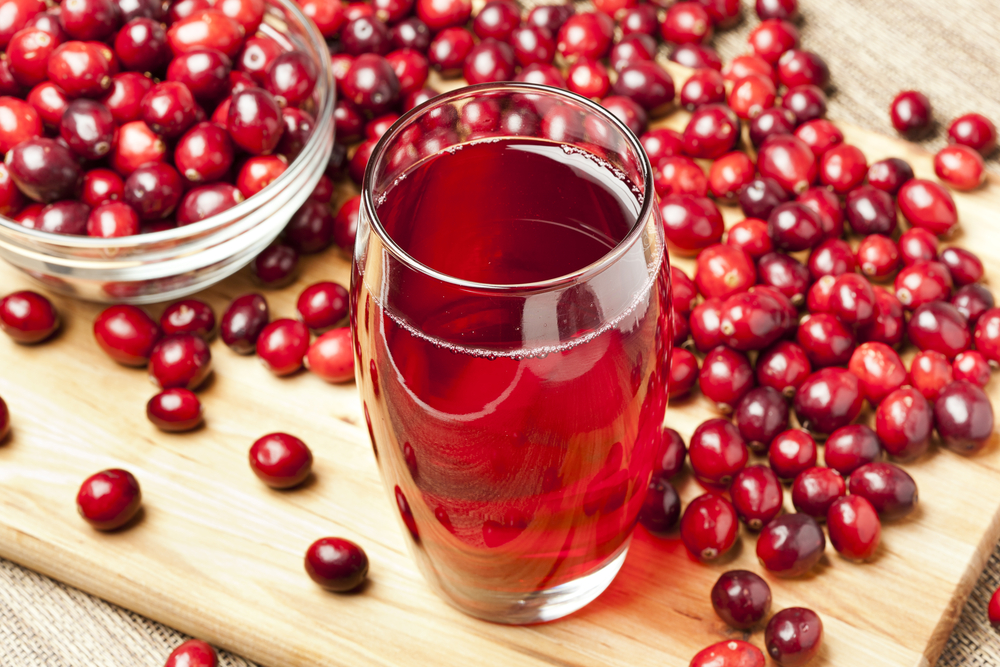 A glass of cranberry juice surrounded by fresh cranberries